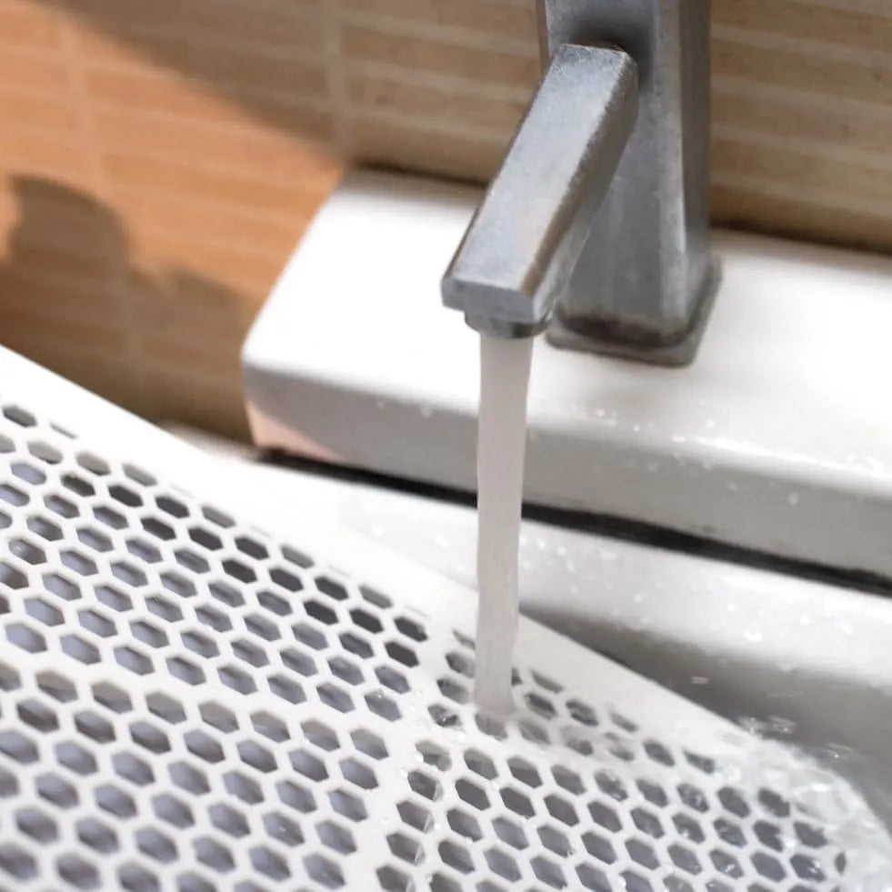 Washing Pet Awesome dog potty tray grid under running water for quick cleaning